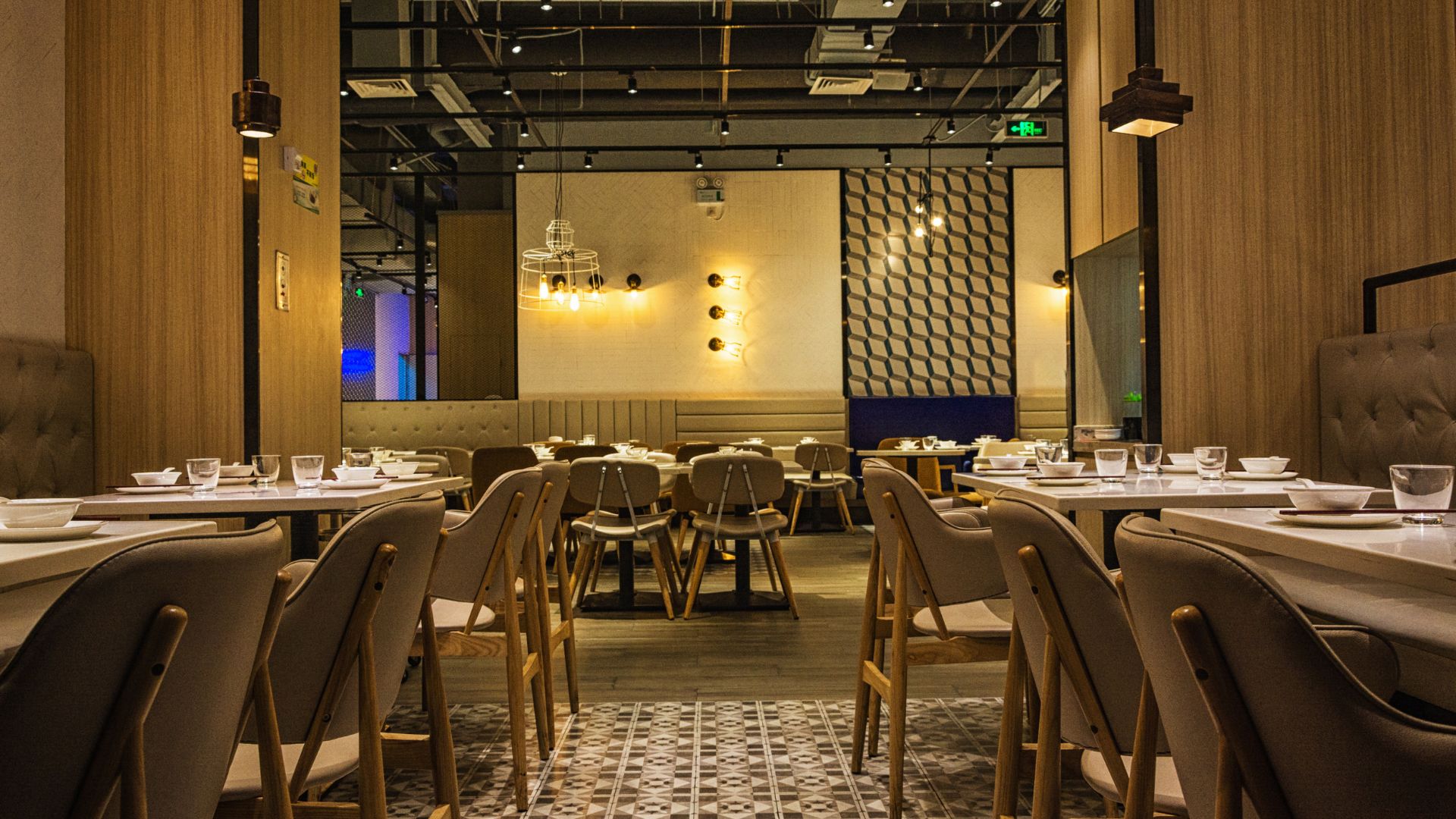Modern restaurant interior with wooden seating booths, dining tables, and warm ambient lighting
