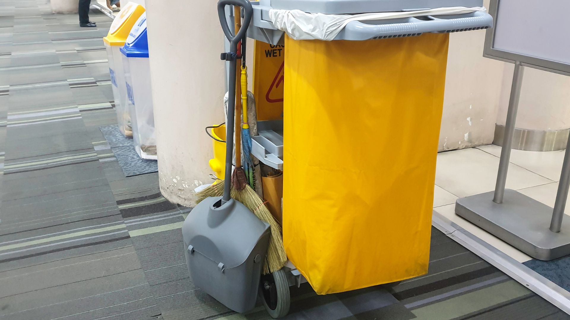 Yellow janitorial cart with cleaning supplies in modern office or public space